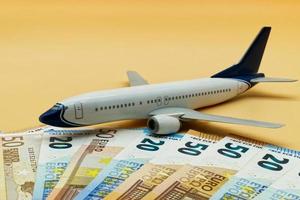 Commercial airplane toy and a pile of Euro banknotes. Flights cost concept photo