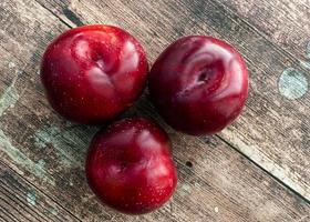 Ripe juicy plums isolated on wooden table photo