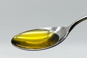 Aceite de oliva virgen extra en una cuchara de plata aislado sobre fondo blanco. foto