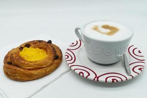 Traditional Italian breakfast, Cappuccino coffee with raisins cream brioche, isolated on white background. photo