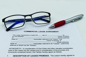 modelo de contrato de arrendamiento comercial sobre una mesa blanca, con gafas y bolígrafo