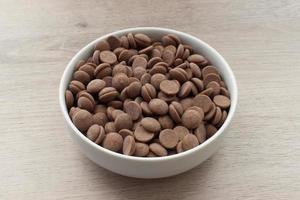 Dark chocolate in a bowl isolated on wooden background photo