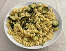 Italian Fusilli pasta with zucchini and olive oil in a white dish. Vegetarian and vegan food. photo