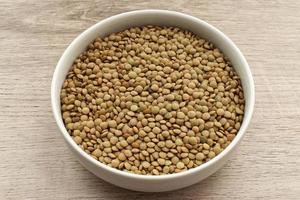 Uncooked Lentils in a bowl isolated on wooden background photo