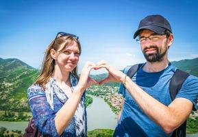 Close up couple forms heart with hand in beautiful location in summer. Georgia travel vacation Mtskheta photo