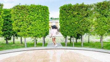 Mujer en movimiento gira de alegría en vacaciones con árboles verdes a los lados foto