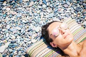 Cerca de la cara de la mujer caucásica en la almohada con rocas playa copypaste antecedentes foto
