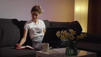 mujer joven toma nota del aprendizaje en línea de la computadora portátil.