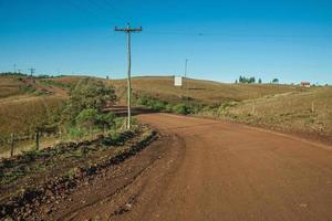 camino de tierra desierto que pasa por tierras bajas rurales llamadas pampas con colinas verdes y árboles cerca de cambara do sul. una pequeña ciudad rural en el sur de Brasil con increíbles atractivos turísticos naturales. foto