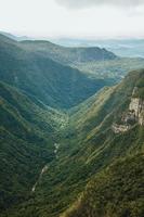 Fortaleza Canyon with steep rocky cliffs covered by thick forest and fog coming up the ravine near Cambara do Sul. A small country town in southern Brazil with amazing natural tourist attractions. photo