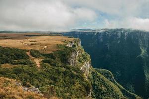 Fortaleza Canyon shaped by steep rocky cliffs with forest and flat plateau covered by dry bushes near Cambara do Sul. A small country town in southern Brazil with amazing natural tourist attractions.