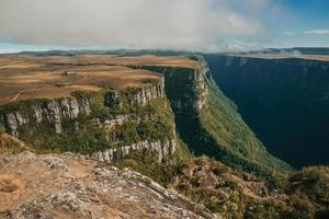 Fortaleza Canyon shaped by steep rocky cliffs with forest and flat plateau covered by dry bushes near Cambara do Sul. A small country town in southern Brazil with amazing natural tourist attractions. photo