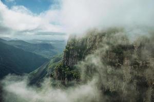 Fortaleza Canyon with steep rocky cliffs covered by thick forest and fog coming up the ravine near Cambara do Sul. A small country town in southern Brazil with amazing natural tourist attractions. photo