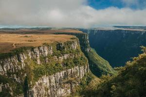 Fortaleza Canyon shaped by steep rocky cliffs with forest and flat plateau covered by dry bushes near Cambara do Sul. A small country town in southern Brazil with amazing natural tourist attractions.