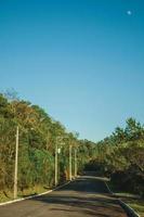 Empty paved street with high-voltage power poles among lush trees near Gramado. A cute european-influenced town in southern Brazil highly sought after by tourists. photo