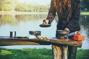 Natural tourist woman, she is doing breakfast, eating food. Travel camping by lake, Travel nature. photo