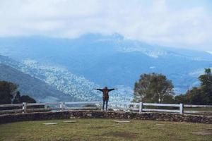 Happy Asian women Travel relax Standing at the view point Look at the watching the nature View of mountains the mist beautiful at sheep farm Doi Inthanon. photo