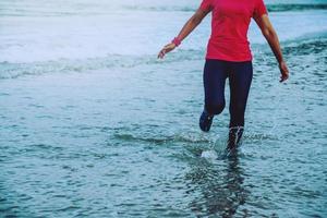 Woman jogging workout on the beach in the morning. Relax with the sea walk. in summer photo