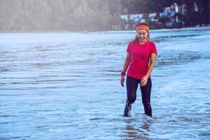 Woman jogging workout on the beach in the morning. Relax with the sea walk. in summer photo