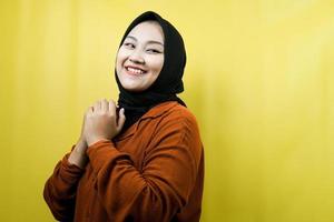 Beautiful young asian muslim woman looking empty space presenting something, confident and cheerful, isolated photo