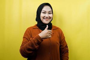 Beautiful young asian muslim woman with thumbs up hand, ok sign, good job, success, congratulations, victory, smiling confident, enthusiastic and cheerful, looking at camera isolated