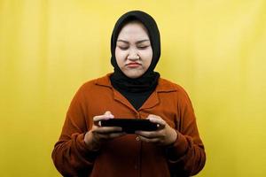 Beautiful asian young muslim woman with hand holding smartphone, playing game, sad, defeat, unhappy, isolated, advertising concept photo