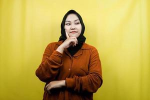 Beautiful and cheerful young asian muslim woman, looking at empty space, presenting something, isolated photo