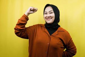 Beautiful asian young muslim woman with raised muscles, strength sign arms, isolated photo