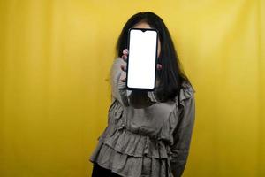 Hermosa mujer joven con manos sosteniendo un teléfono inteligente con pantalla en blanco o en blanco, promoviendo la aplicación, promocionando algo, alegre y confiada, publicidad, aislado foto