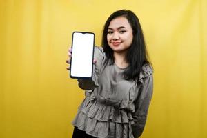 Hermosa mujer joven con manos sosteniendo un teléfono inteligente con pantalla en blanco o en blanco, promoviendo la aplicación, promocionando algo, alegre y confiada, publicidad, aislado foto