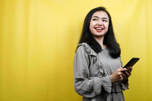 Hermosa mujer joven con las manos sosteniendo el teléfono inteligente, mirando el espacio vacío, promocionando el producto, presentando algo, publicidad, aislado foto