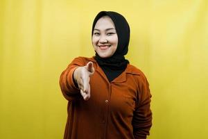 Beautiful young asian muslim woman with hands shaking the camera, hands sign of cooperation, hand sign of agreement, hand sign of friendship, isolated photo