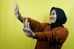 Beautiful asian young muslim woman with hand rejecting something, hand stopping something, disliking something in empty space, isolated photo