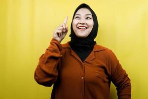 Beautiful young asian muslim woman with hands pointing up, getting ideas, coming up with solutions, presenting something, isolated, advertising concept photo