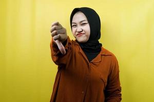 Beautiful young asian muslim woman with dislike hand, bad, looking at camera isolated photo