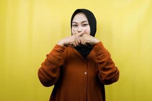 Hermosa joven musulmana asiática con el dedo en la boca, diciendo que se calle, no hagas ruido, baja la voz, no hables, aislado