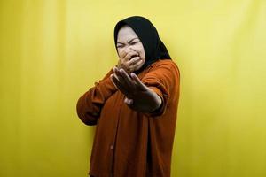 Beautiful young asian muslim woman with hand covering mouth, refusing something isolated photo