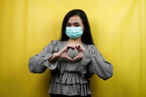 Beautiful young woman wearing a mask with love hands, i love you, isolated photo