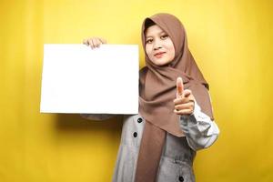 Pretty young muslim woman cheerful holding blank empty banner, placard, white board, blank sign board, white advertisement board, presenting something in copy space, promotion photo