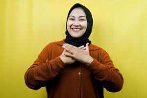 Beautiful young asian muslim woman smiling surprised and cheerful, with hands holding chest, excited, not expecting, looking at camera isolated
