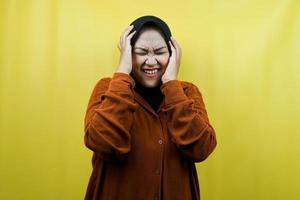 Hermosa joven musulmana asiática estresada, conmocionada, mareada, infeliz, con muchos problemas, quiere solución, con las manos sosteniendo la cabeza aislada foto