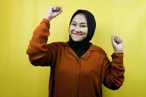 Beautiful asian young muslim woman with raised muscles, strength sign arms, isolated photo