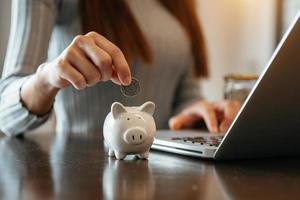 woman hand putting coin into piggy bank photo