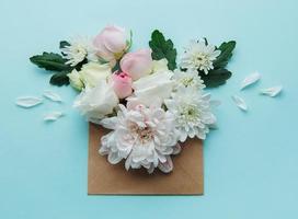 Envelope with pink flowers on blue background. photo