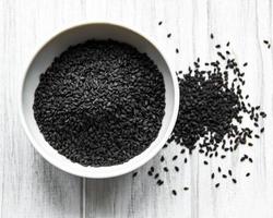 Black sesame seeds in a spoon on a rustic table