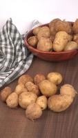 Fresh small potatoes for cooking in a wooden bowl. With copy space  on white background. photo