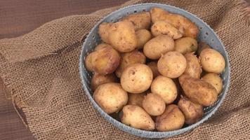 Fresh small potatoes for cooking in a wooden bowl. With copy space  on white background. photo