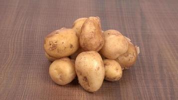 Fresh small potatoes for cooking in a wooden bowl. With copy space  on white background. photo