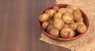 Fresh small potatoes for cooking in a wooden bowl. With copy space  on white background. photo