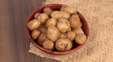 Fresh small potatoes for cooking in a wooden bowl. With copy space  on white background. photo